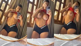 Micha Vargas, uma mulher com um corpo avantajado, está gravando vídeos no quarto de sua casa exibindo seus peitões e atraentes